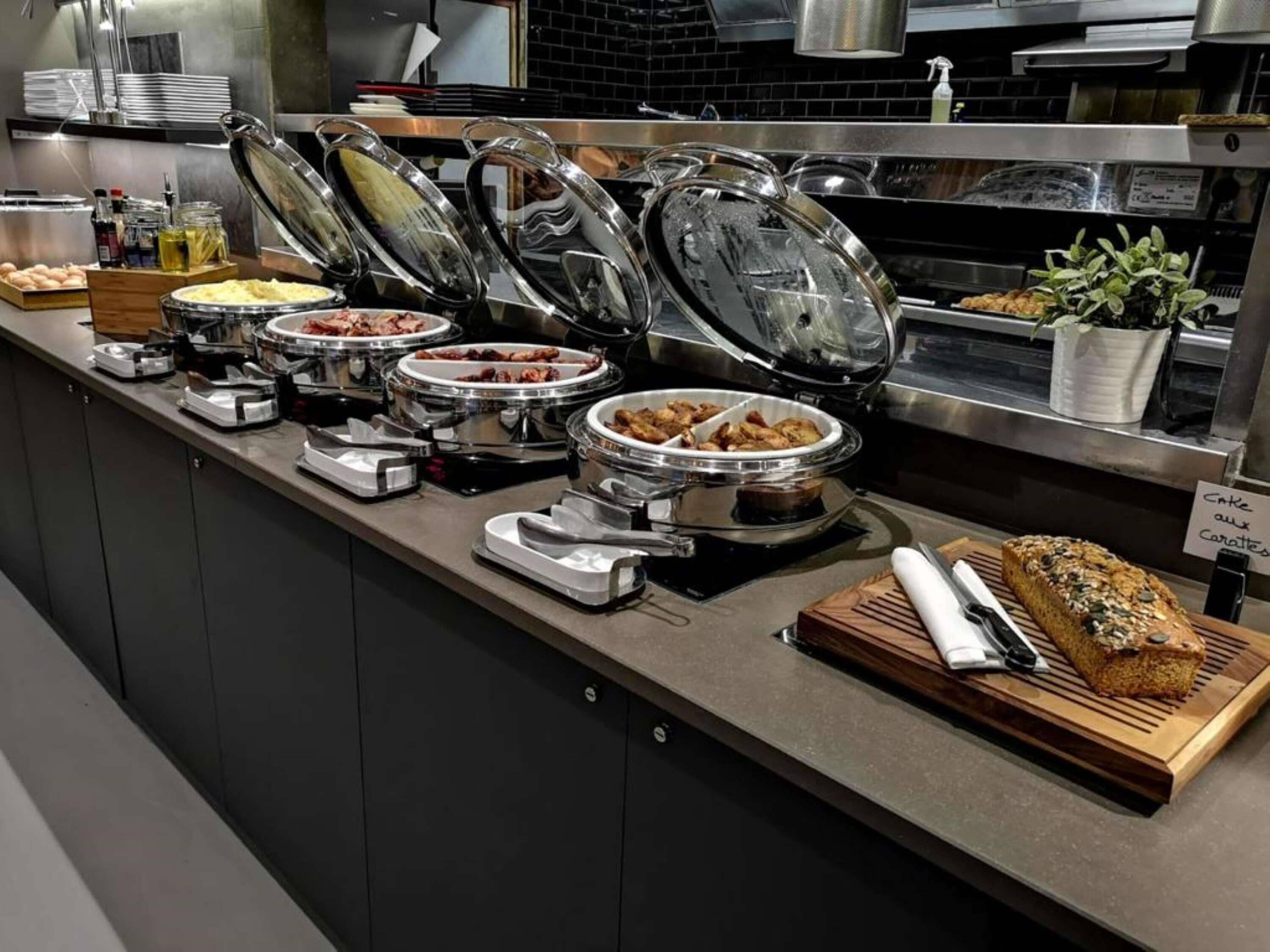 A buffet setup with various food items and a loaf of bread on a wooden board.