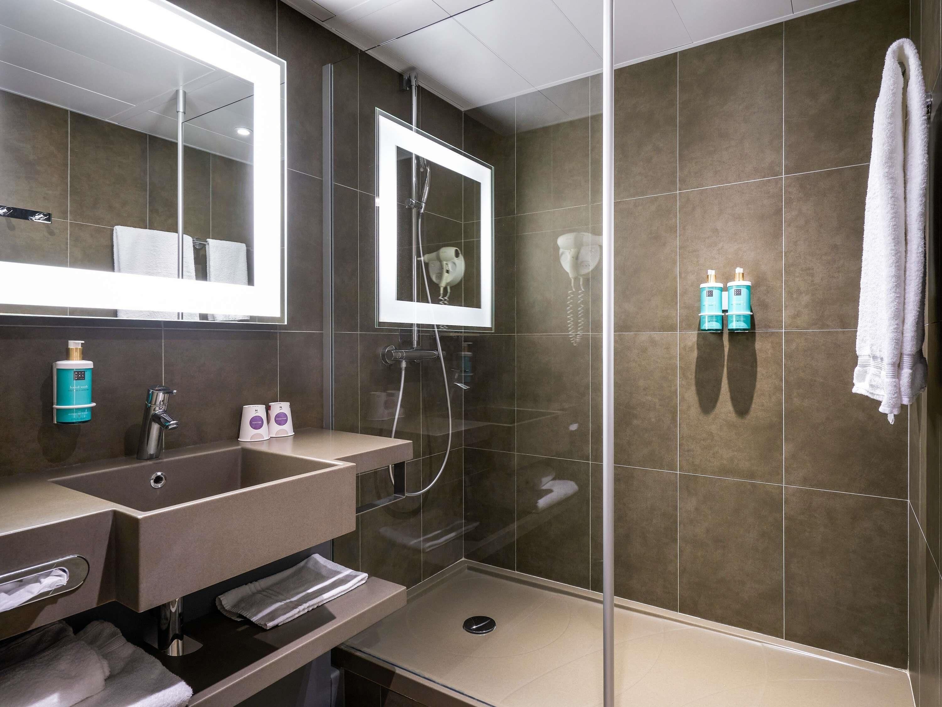 Une salle de bain moderne avec une douche à parois de verre, un meuble-lavabo avec un miroir et un porte-serviettes.