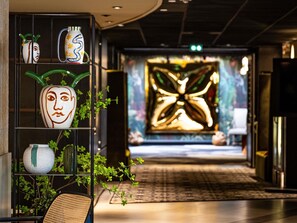 A hallway with a decorative wall and a plant on the left. - Novotel Marne Vallee Collegien (Collegien)