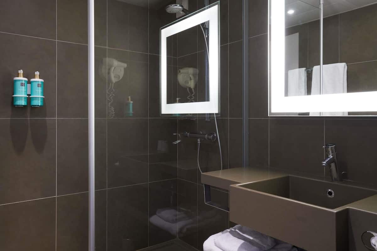 A modern bathroom with a glass shower enclosure, a vanity with a mirror, and a towel rack.
