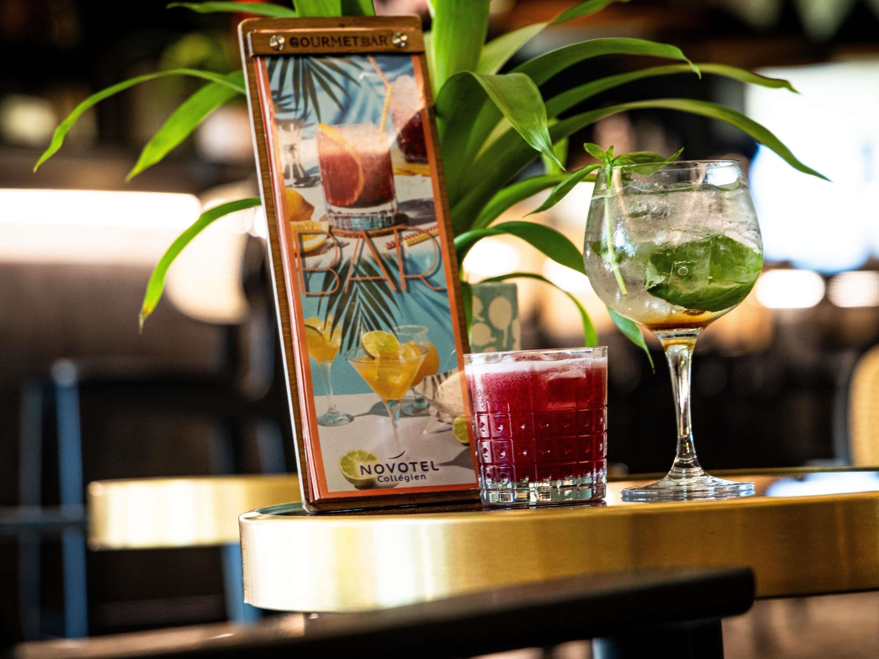 Eine Getränkekarte im tropischen Stil, ein Glas roter Drink und ein Glas mit Limettenscheibe.
