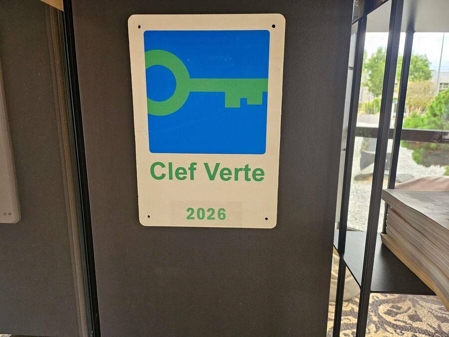 Een bord met een sleutelsymbool en de tekst 'Clef Verte 2026' op een muur.