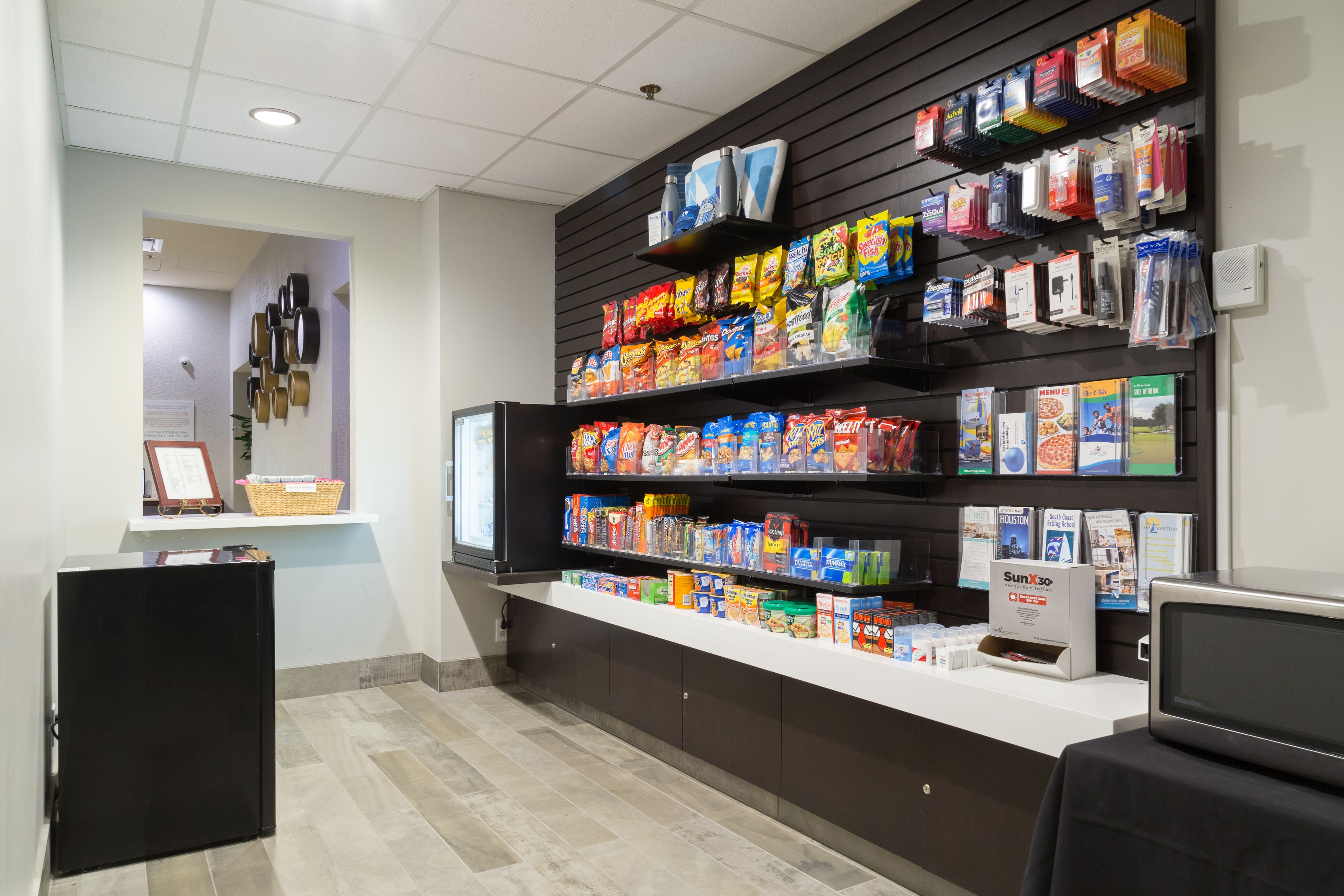 A snack bar with shelves stocked with various packaged snacks and beverages, a refrigerator, and a microwave.