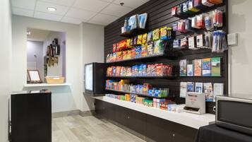 A snack bar with shelves stocked with various packaged snacks and beverages, a refrigerator, and a microwave.