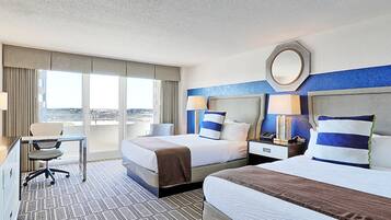 A hotel room with two beds, a desk, and a chair.