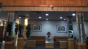 Eine Lobby mit einem großen Kronleuchter, zwei Sofas, einem Couchtisch und einer Topfpflanze.