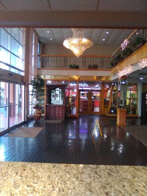 A spacious lobby with a large chandelier, potted plants, and a polished floor.