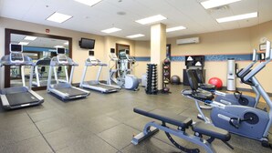 Ein Fitnessstudio mit Laufbändern, Crosstrainern und Krafttrainingsgeräten.