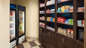 Ein Verkaufsautomatenbereich für Snacks und Getränke, mit Kühlschrank und Regalen voller verschiedener Produkte.