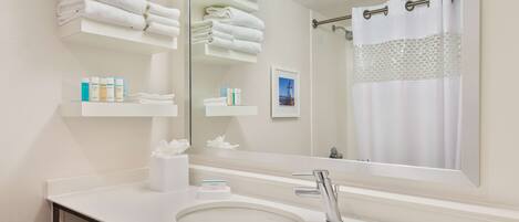 A modern bathroom with a large mirror, white sink, and towel racks.