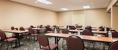 A conference room with multiple tables and chairs, equipped with water bottles and papers.