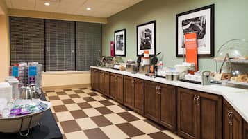 Una cocina de hotel con suelo a cuadros, una barra libre y cuadros en la pared.
