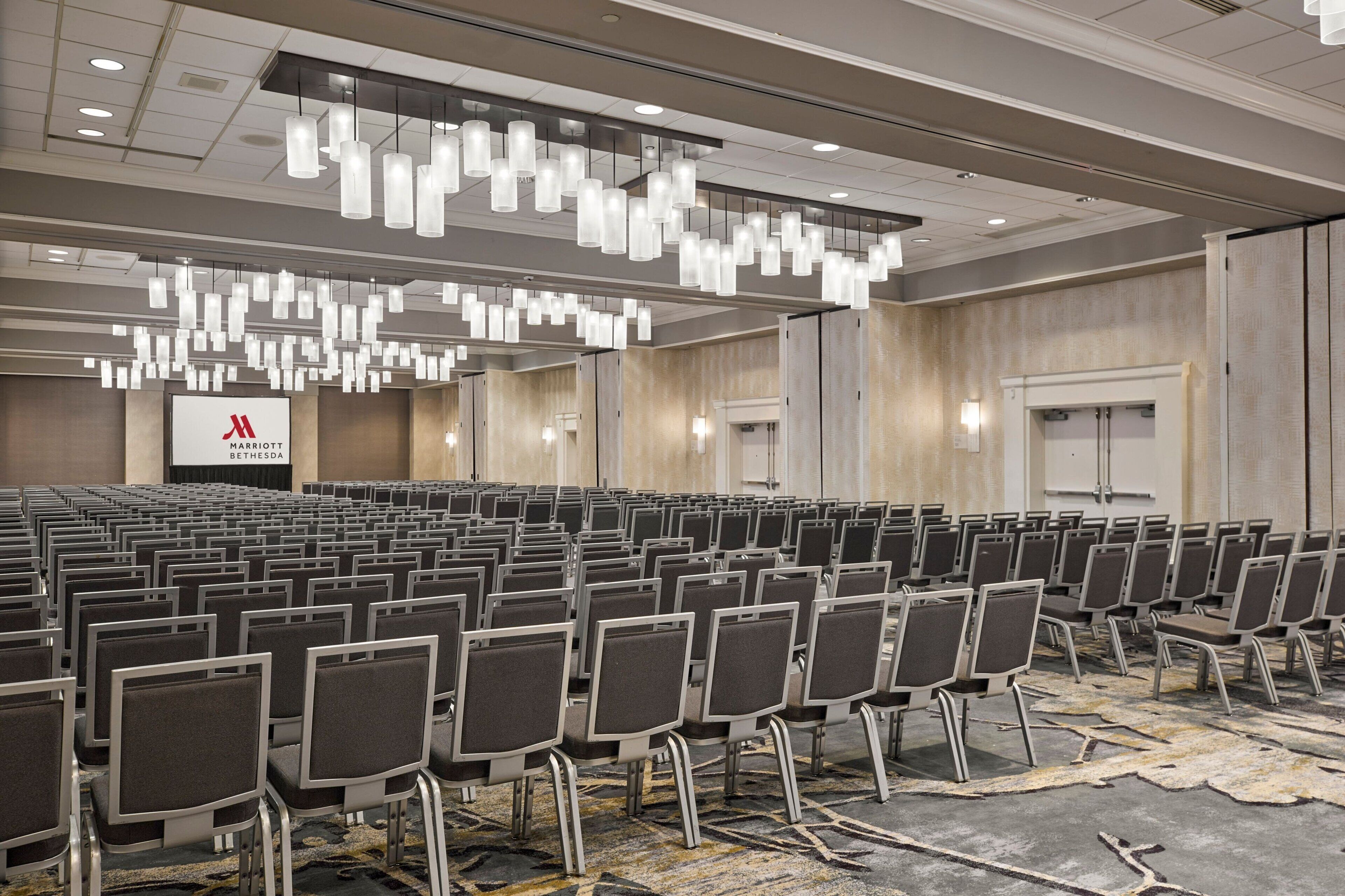 A large conference room with rows of chairs, a stage, and a Marriott sign.