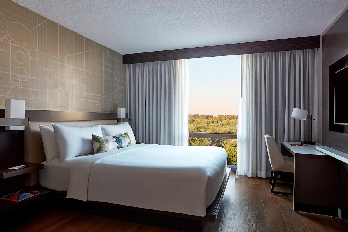 A modern hotel room with a large bed, a desk, and a TV.