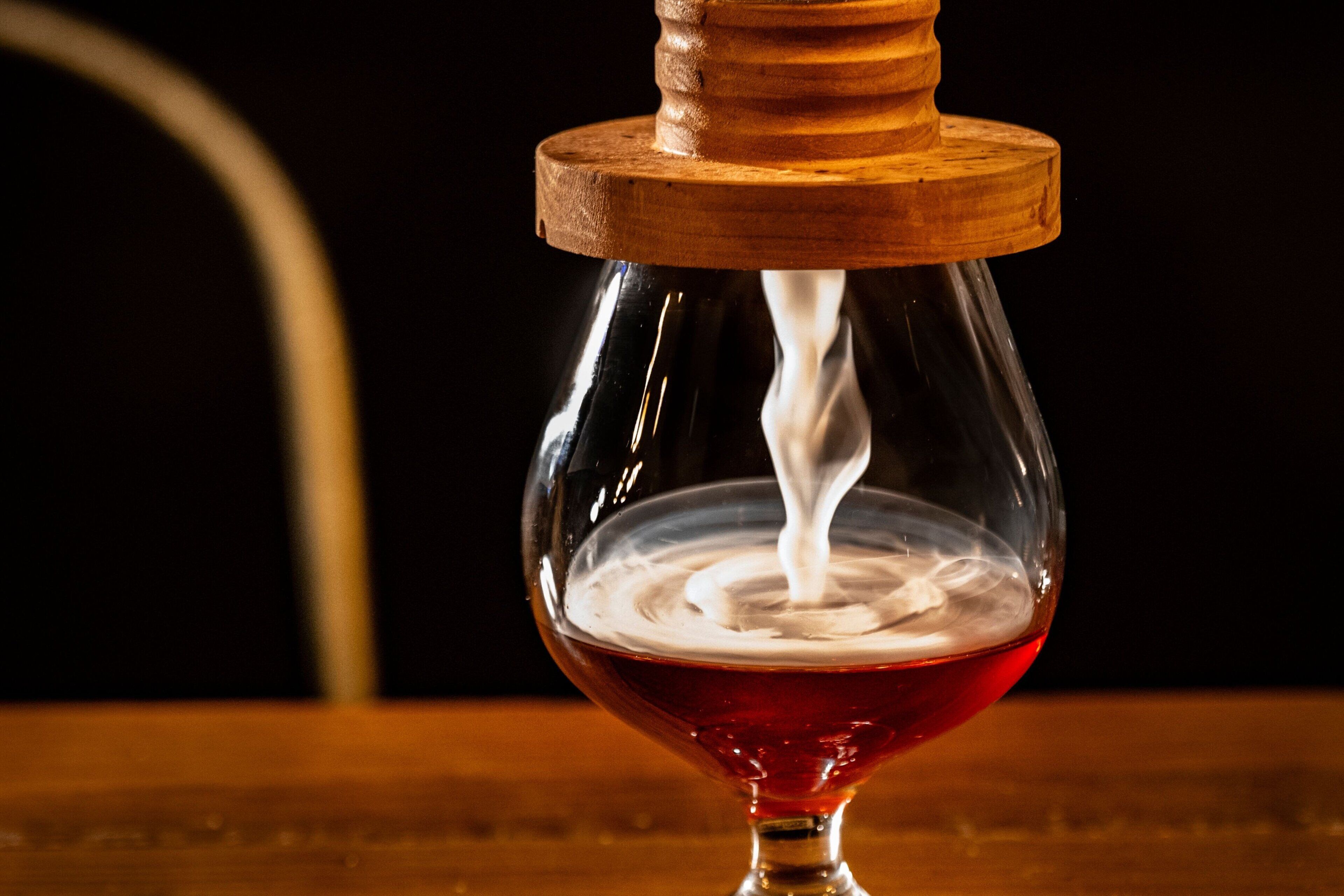 Ein Glas mit Holzfuß, in das eine rote Flüssigkeit gegossen wird.