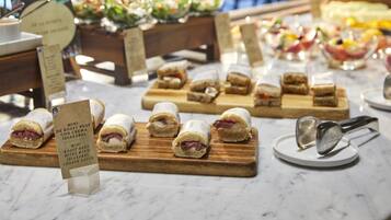 Una mesa de buffet con diversos alimentos, incluyendo bocados de roast beef con salsa de queso Idiazabal.