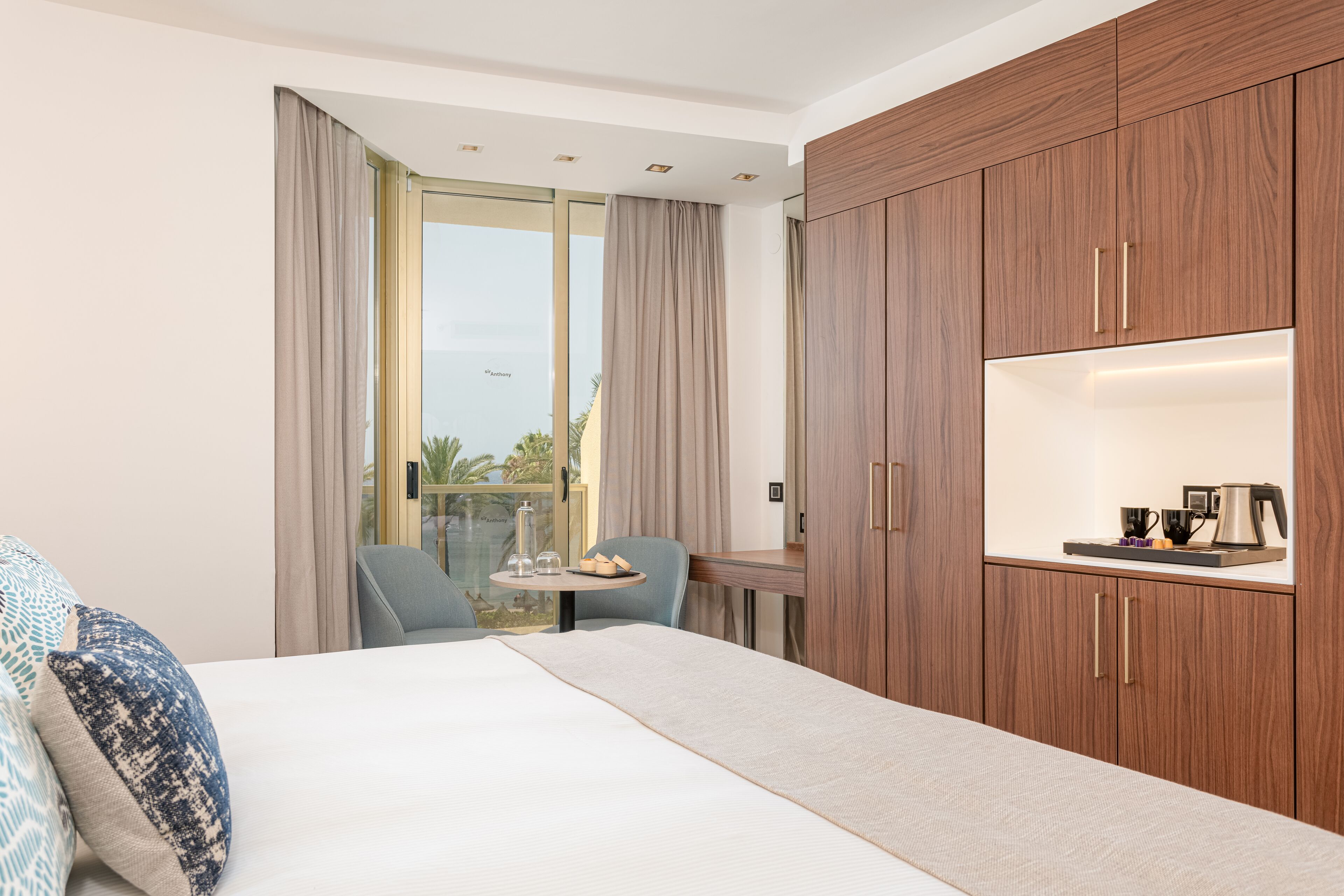 Una habitación de hotel con cama, escritorio, silla y armario.