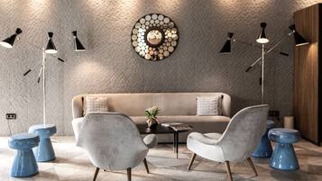 A modern living room with a beige sofa, two grey armchairs, a coffee table, and a decorative wall piece.