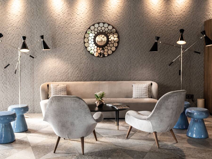 A modern living room with a beige sofa, two grey armchairs, a coffee table, and a decorative wall piece.