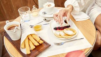 A breakfast setting with pancakes, a cup of coffee, and a plate of fresh berries.