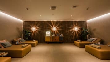 Un cuarto de spa con dos camillas de masaje, una pared de madera con iluminación tipo estrella y un mostrador de recepción, además de una planta en maceta.