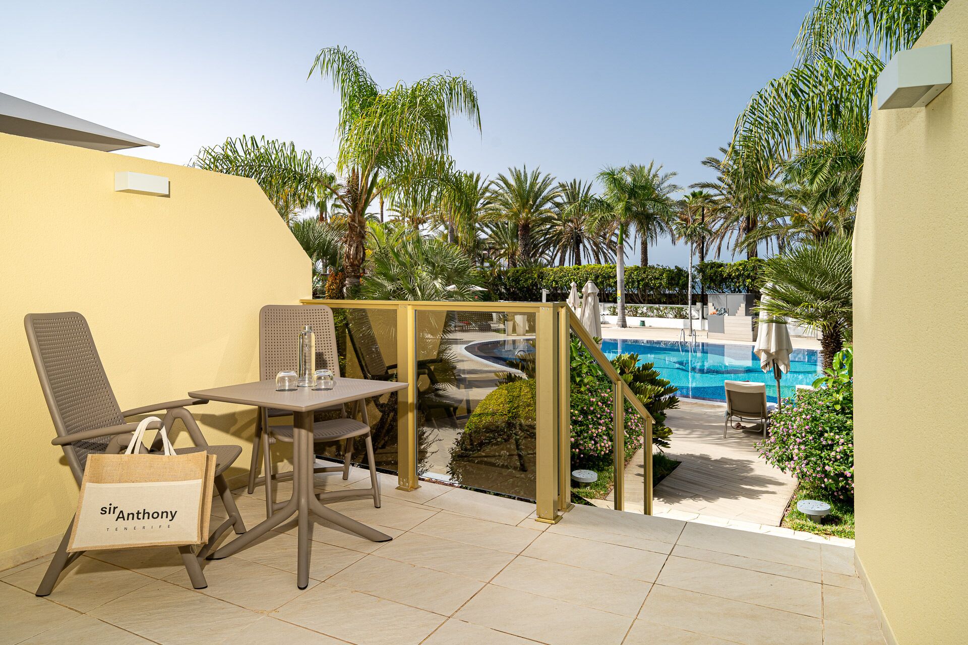 A patio area with a pool, a table with chairs, and a lounge chair.