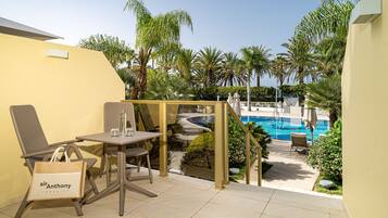 A patio area with a pool, a table with chairs, and a lounge chair.