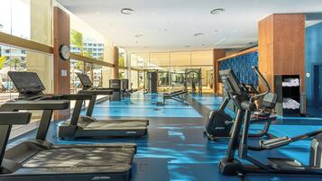A modern gym with treadmills, ellipticals, and weight machines.
