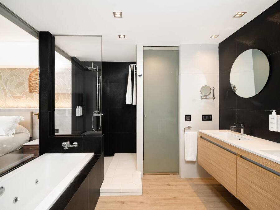Een moderne badkamer met een groot bad, een douche en een wastafel met spiegel.