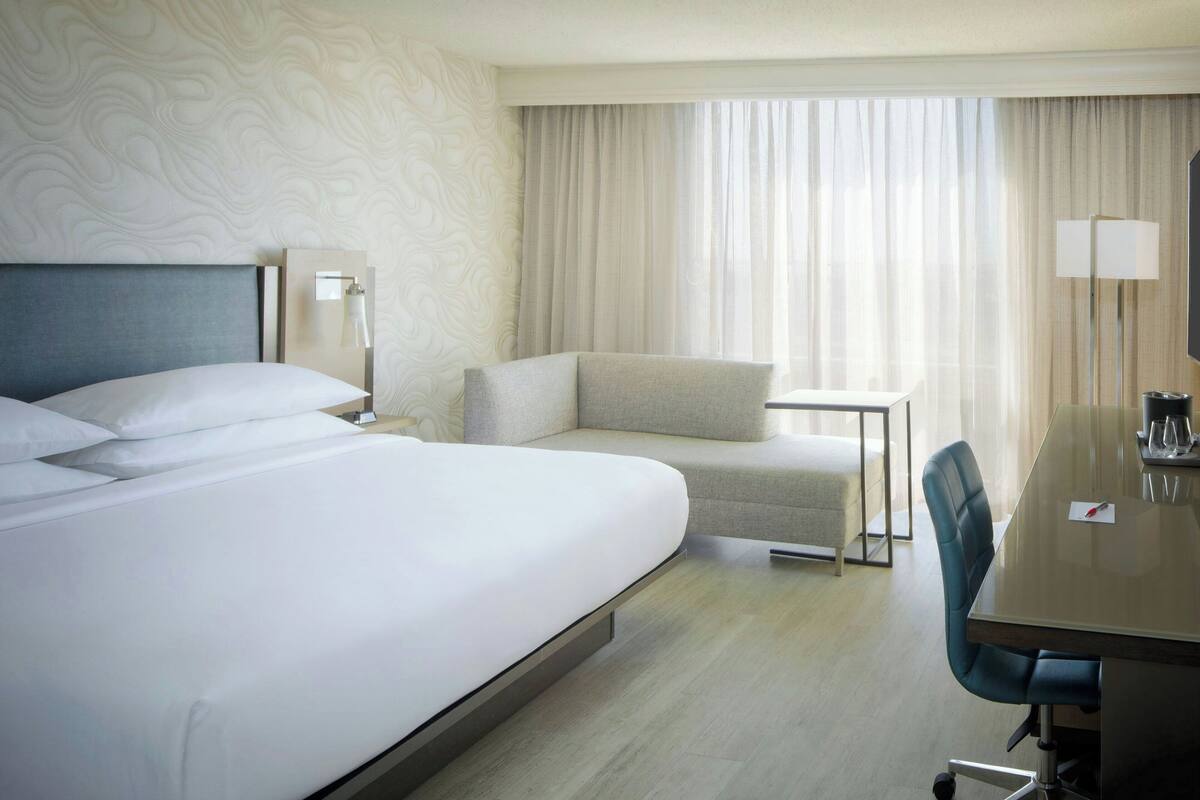 Habitación de hotel con una cama grande, un escritorio, una silla y un televisor.