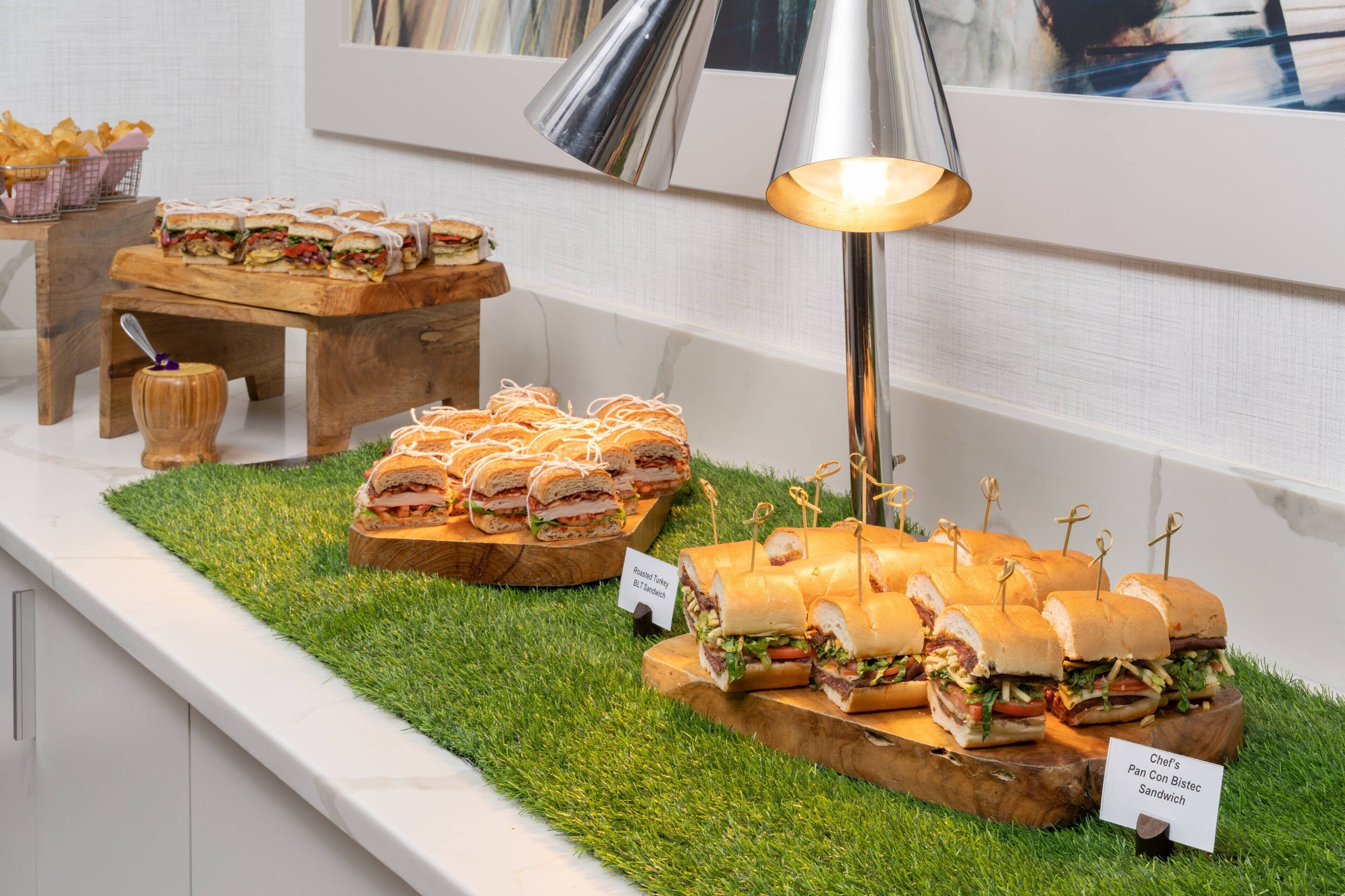 Un buffet proposant divers sandwichs présentés sur des planches en bois, avec un panneau indiquant quel sandwich est proposé.