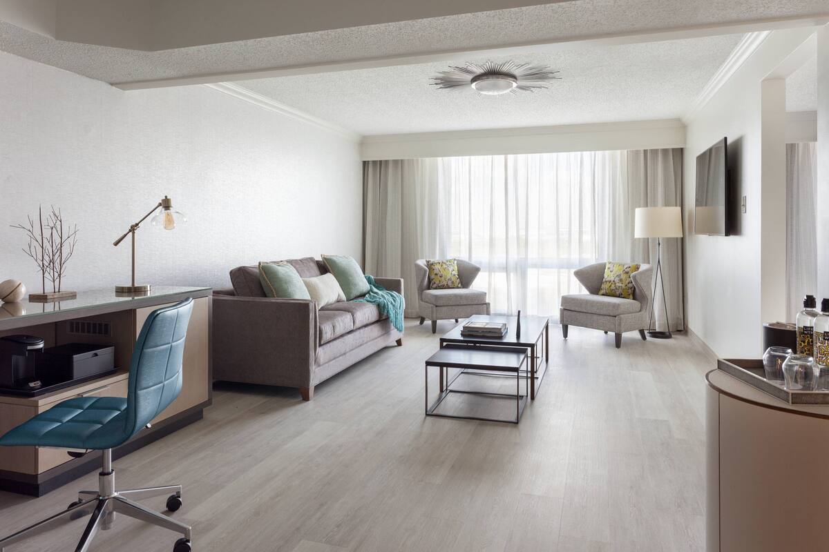 Una sala de estar moderna con un sofá, sillones, una mesa de centro y un escritorio con una silla.