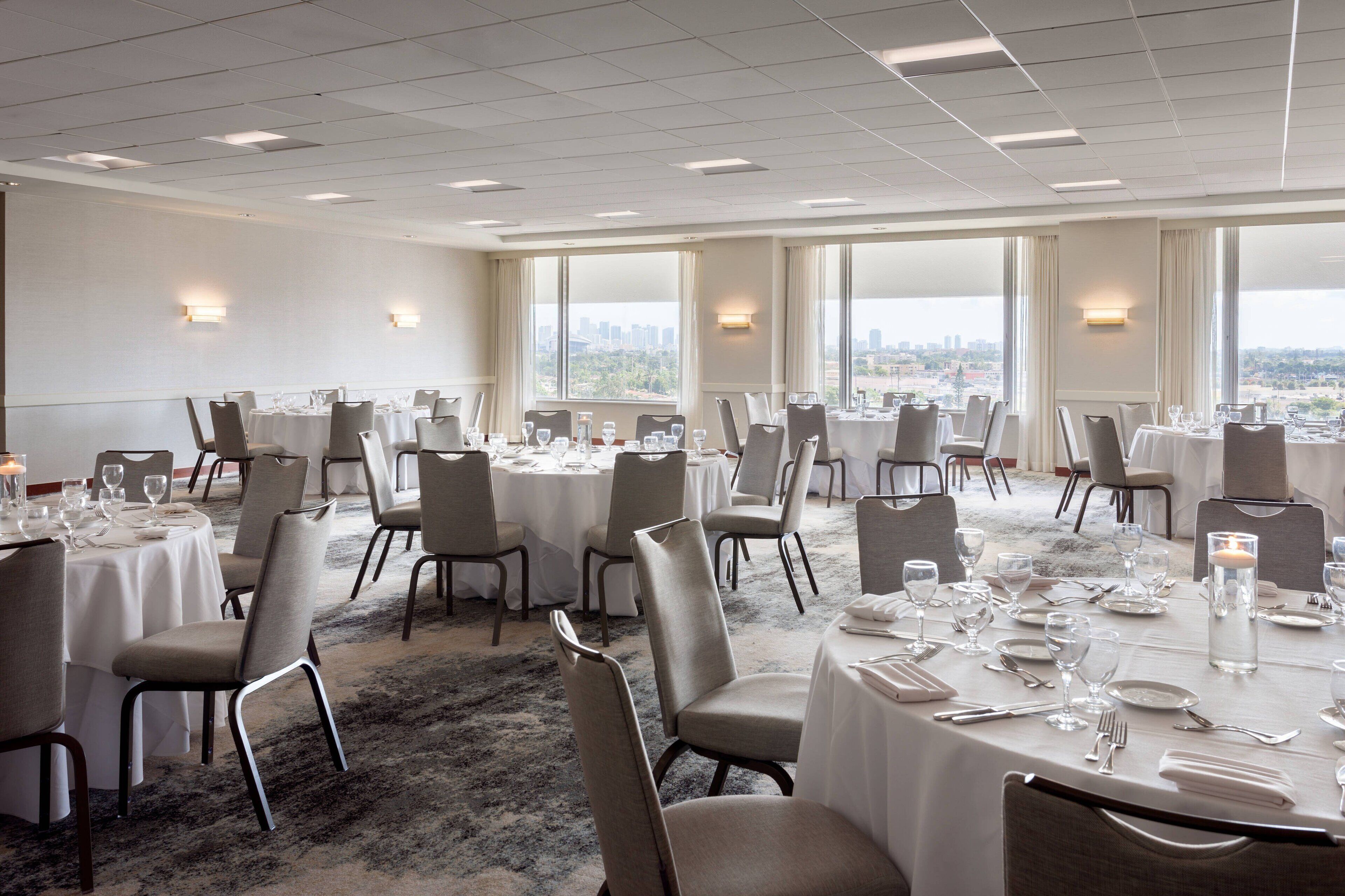 A conference room with round tables, chairs, and a carpeted floor.