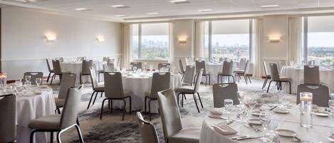 A conference room with round tables, chairs, and a carpeted floor.