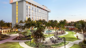 Ein Marriott Hotel mit modernem Design, das einen großen Pool, Sitzbereiche im Freien und üppige Bepflanzung bietet.