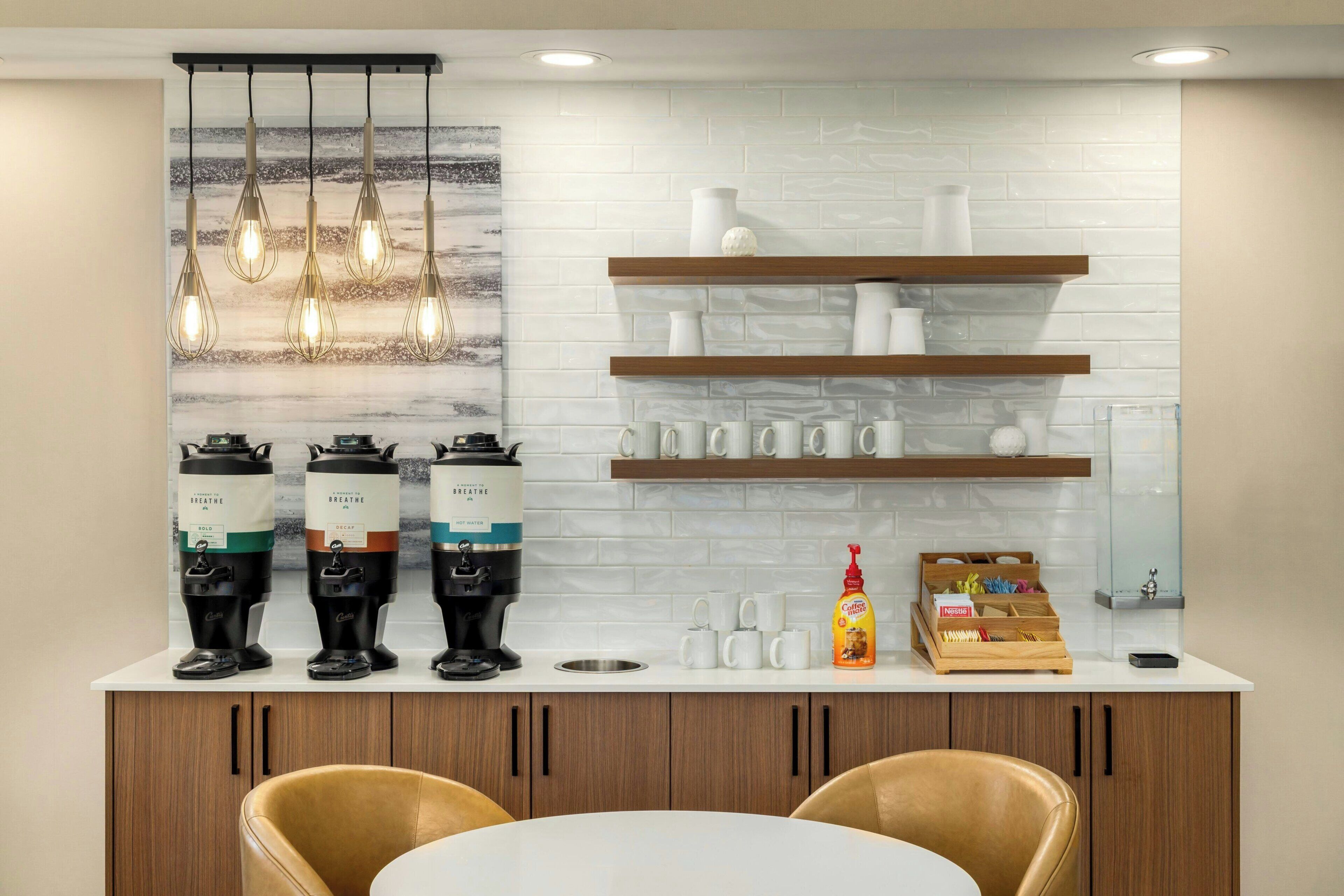 A modern kitchen with a coffee station, white tiled backsplash, and wooden shelves.