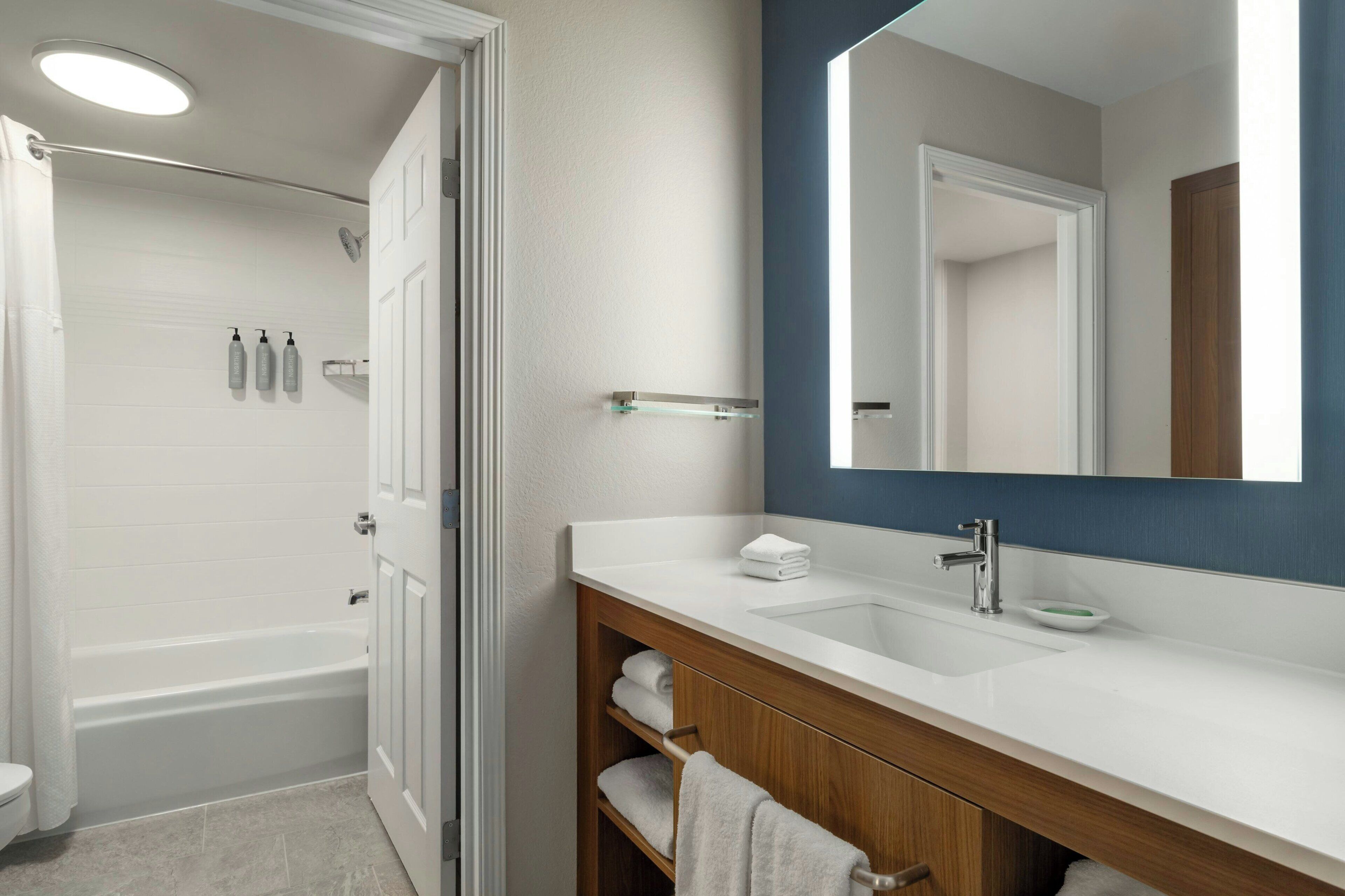 A bathroom with a bathtub, a sink with a mirror, and a towel rack.