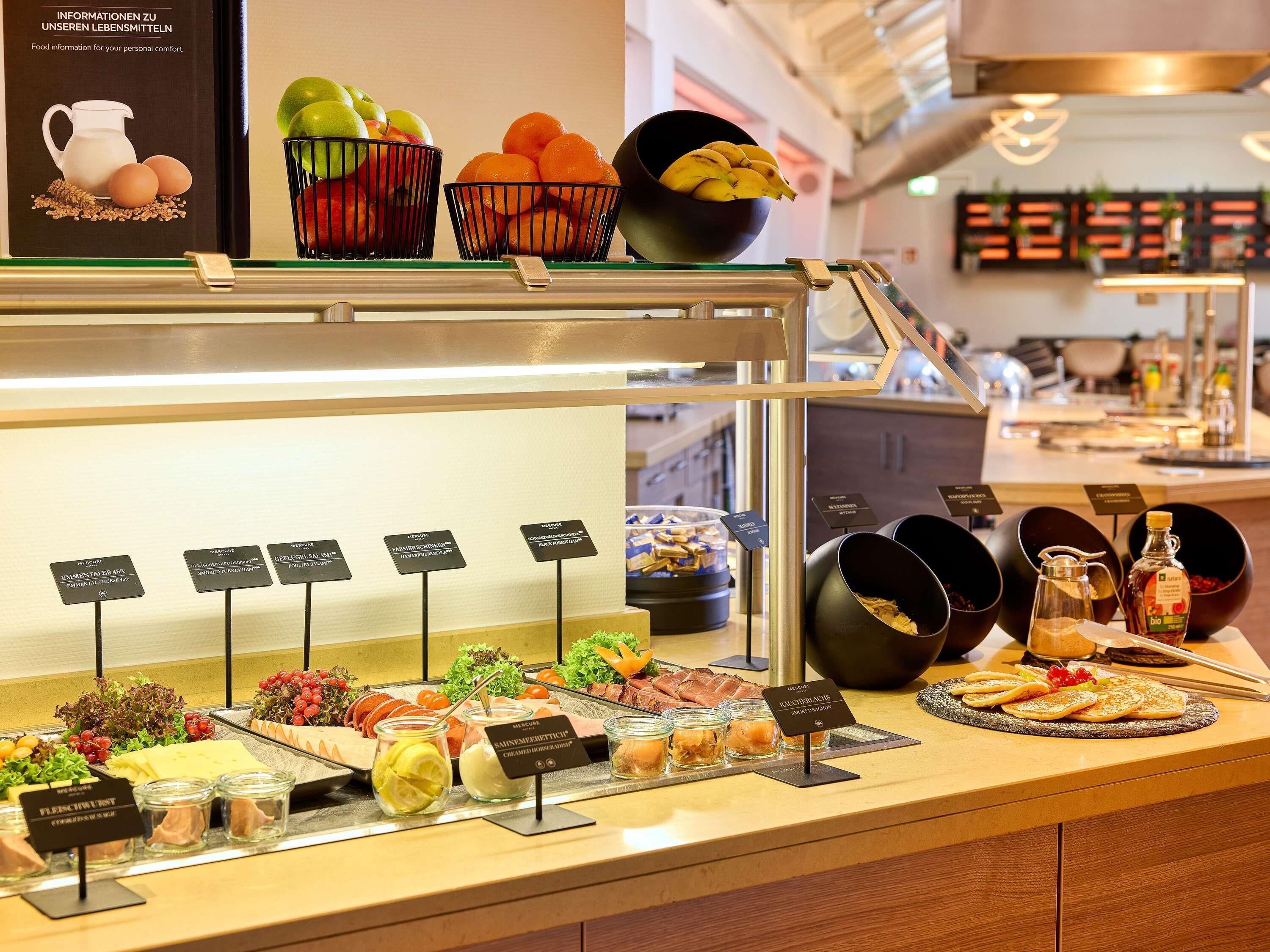 Ein reichhaltiges Buffet mit verschiedenen Speisen und Schildern, die die Gerichte beschreiben.