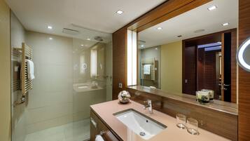 Un baño moderno con un espejo grande, un lavabo y una ducha con cerramiento de vidrio.