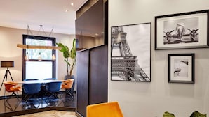 Un interior moderno con comedor, una planta grande en maceta y obras de arte en la pared.