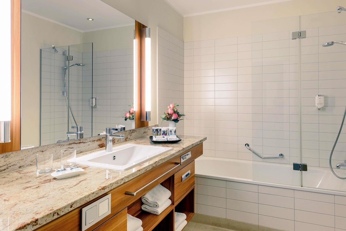 A modern bathroom with a large mirror, a sink, a shower, and a bathtub.