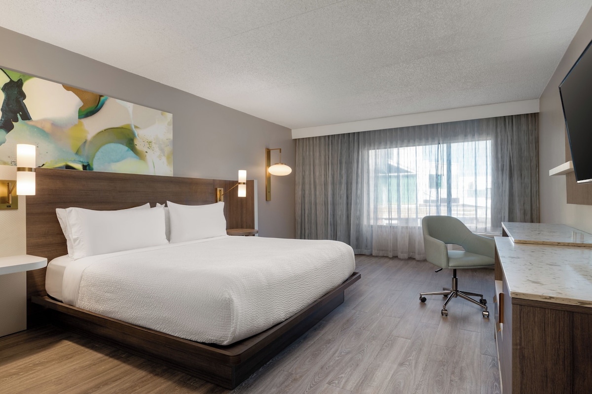 Een hotelkamer met een groot bed, een bureau, een stoel en een televisie.