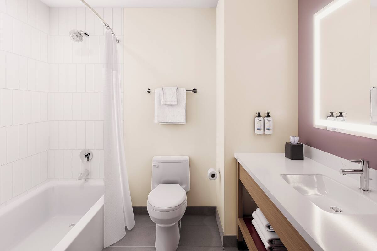 A modern bathroom with a bathtub, toilet, and vanity with a mirror.