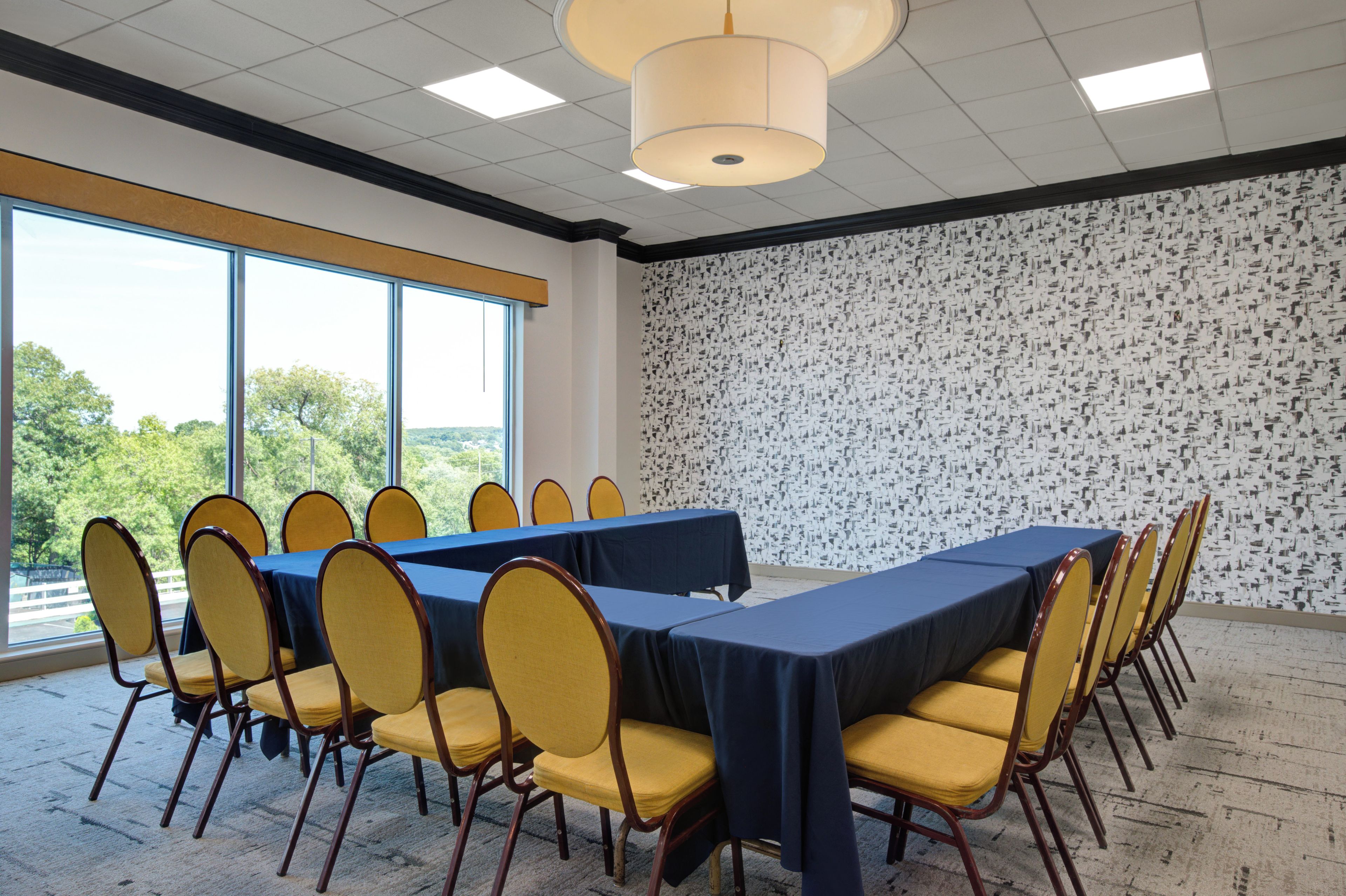 A conference room with a long table, yellow chairs, and a patterned wall.