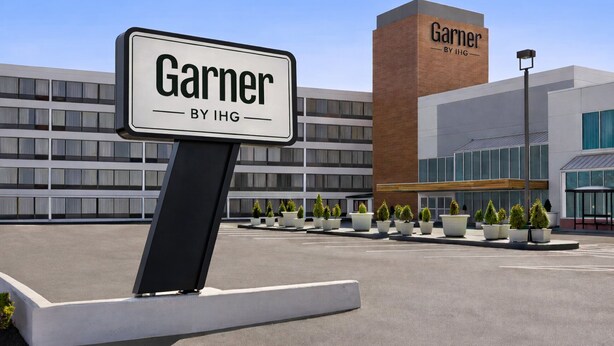 A sign for 'Garner by IHG' in front of a modern building with multiple windows and a brick facade. - Garner Hotel Totowa by IHG (Totowa)