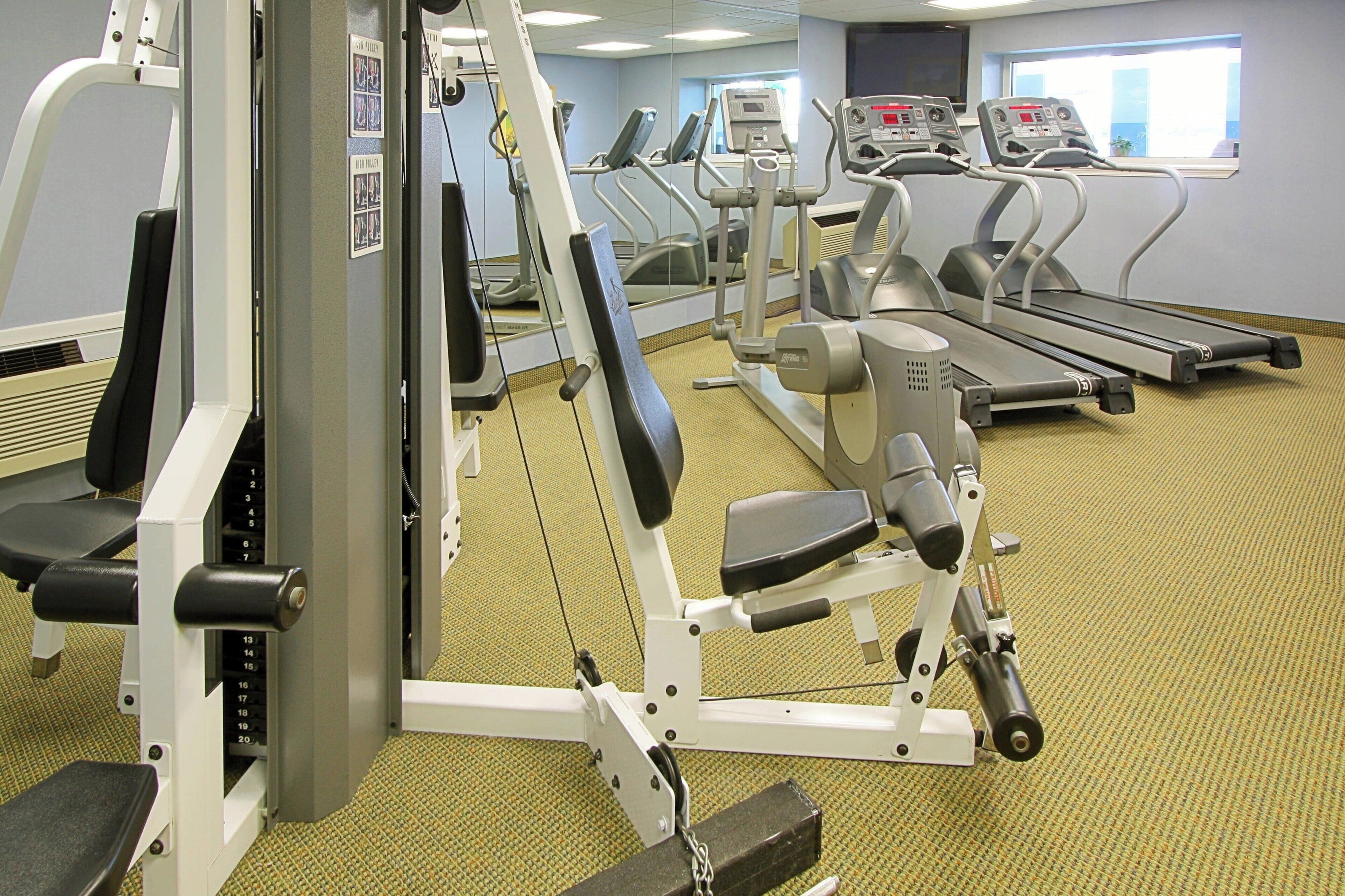 A gym with various exercise equipment including treadmills, a weight machine, and a bench.