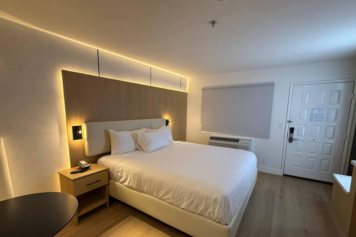 A modern hotel room with a large bed, bedside tables, a desk, and a chair.