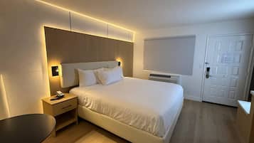 Een moderne hotelkamer met een groot bed, nachtkastjes, een bureau en een stoel.