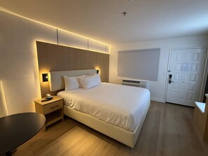 A modern hotel room with a large bed, bedside tables, a desk, and a chair.