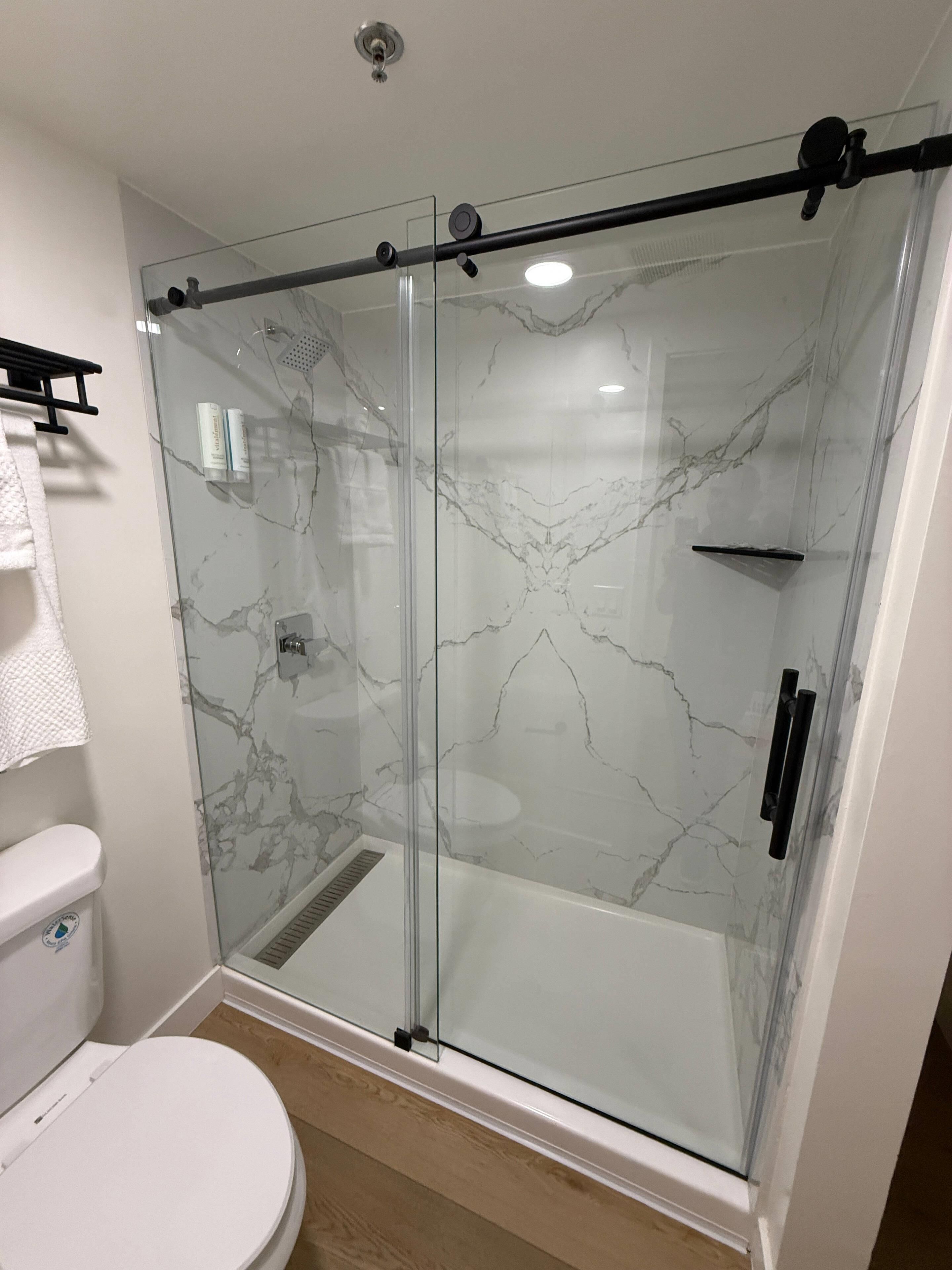A modern bathroom with a glass-enclosed shower, a white toilet, and a marble backsplash.